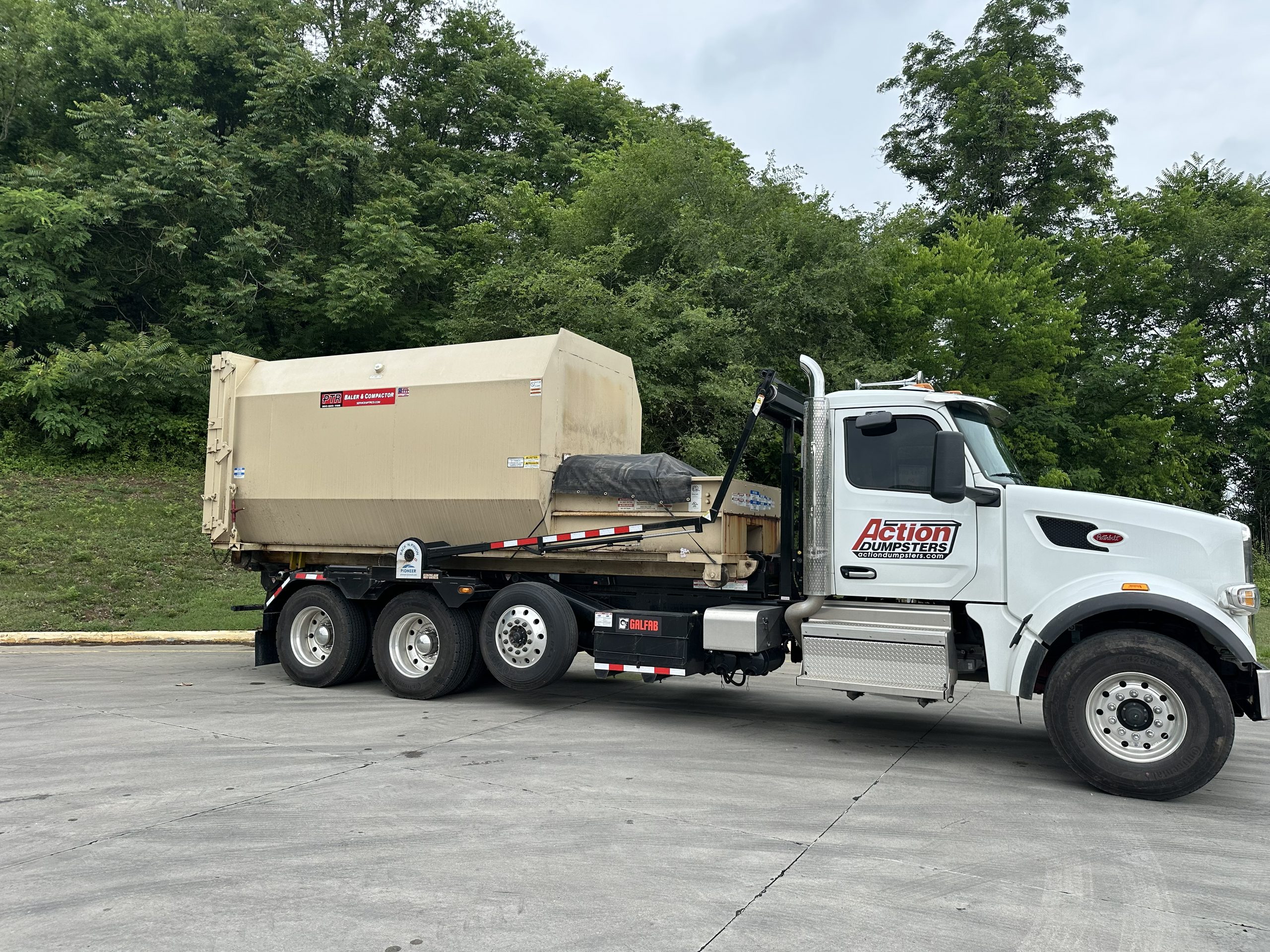 Action Dumpsters Peterbilt truck hauling a PTR compactor