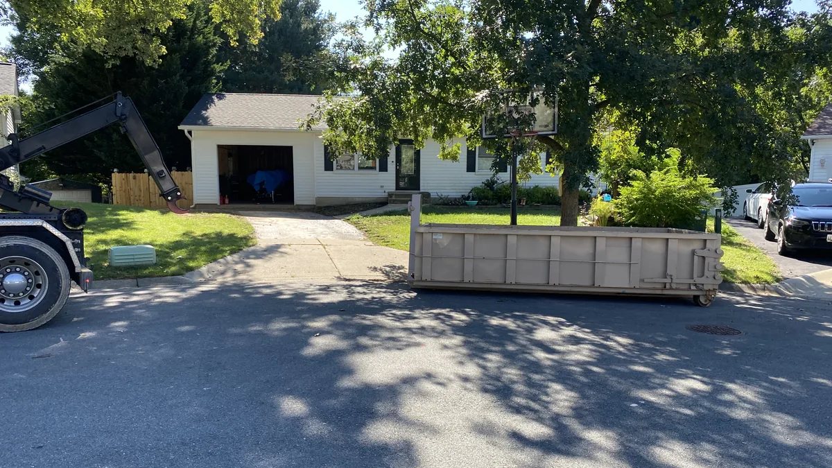 Tan roll-off dumpster placed in front of a house after truck delivery in the Damascus, MD area
