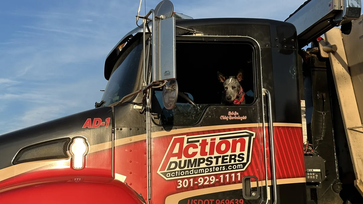 Close-up of an Action Dumpsters truck cab with the logo and phone number, serving Olney, MD
