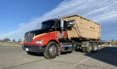 Action Dumpsters roll-off truck carrying a 30 yard dumpster in a parking lot